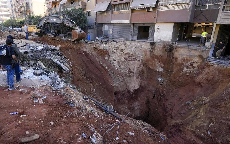 People look at a huge hole in the ground in a suburb of Beirut.