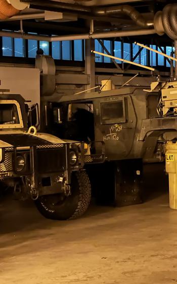 A bear sits in a Humvee.