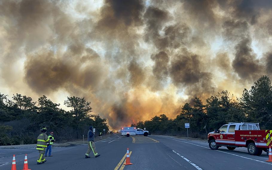 Smoke and fire in the background as firefighters and rescue workers respond.