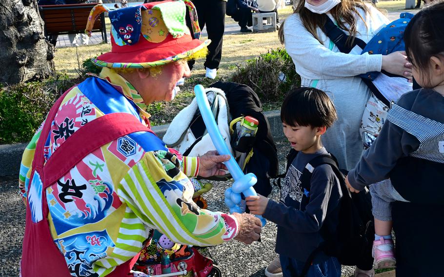 A clown hands a balloon sword to a visitor at the annual Spring Festival.