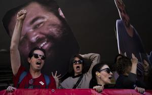 People raise their fists in protest while carrying posters of hostages.