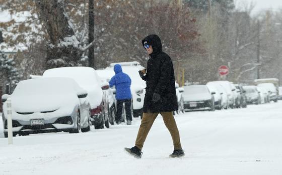 A pedestrian crosses First Avenue as a winter storm sweeps over the intermountain West, plunging temperatures into the single digits and bringing along a light snow in its wake Saturday, Jan. 18, 2025, in Denver. (AP Photo/David Zalubowski)