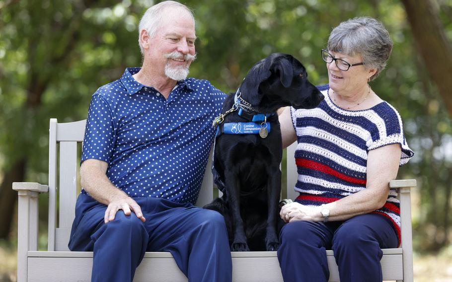 Veteran Kathy Schneider with her dog Dakota and husband Ray share a moment in between a portrait session on during a service dog graduation ceremony July 14, 2023, at Baylor Scott & White Health in Irving, Texas. Schneider suffers from post-traumatic stress disorder after serving 30 years on and off active duty as an embedded combat nurse.