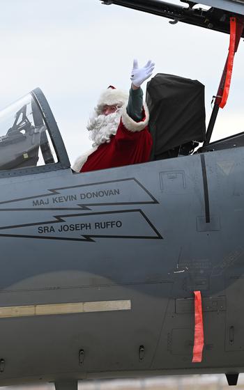 Santa Claus waves from the cockpit of an aircraft.