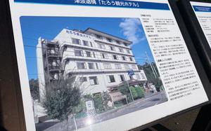 A sign displays Japanese writing and a photo of a multi-story hotel.