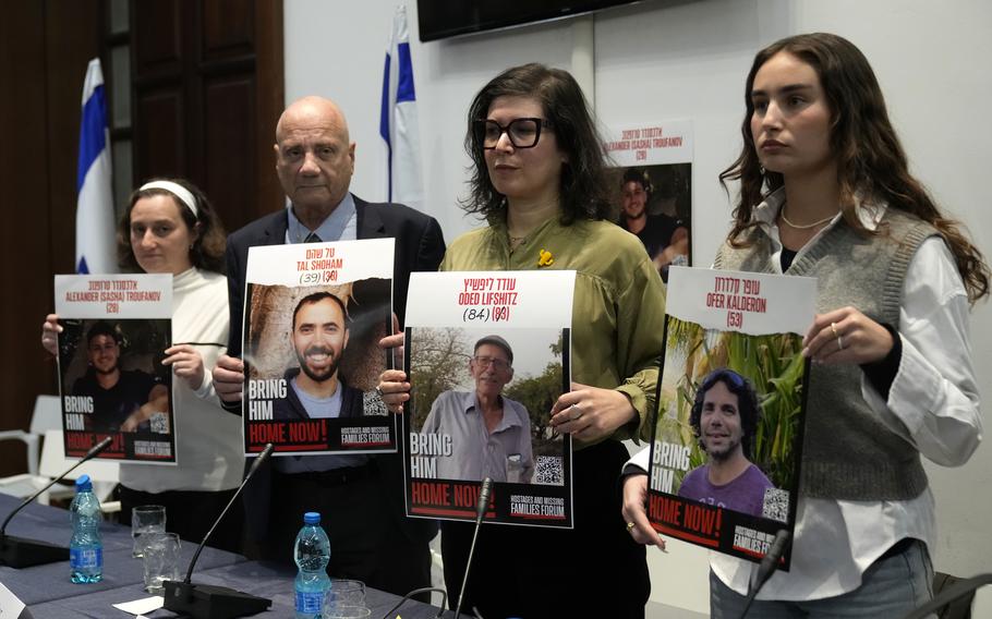 Former Israeli hostages and relatives of some still being held by Hamas hold photos during a news conference.