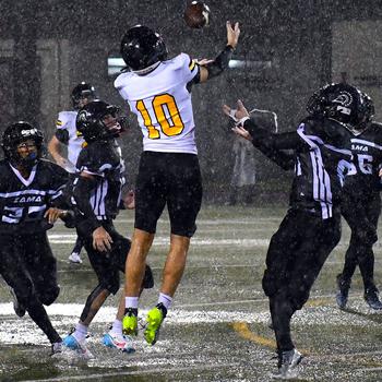 American School In Japan's Shou Murakami-Moses skies for a pass, surrounded by four Zama defenders and in a driving rain.