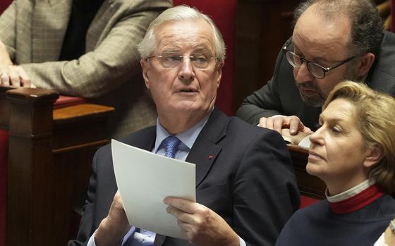 French Prime Minister Michel Barnier holds a document during speeches at the National Assembly prior to a no-confidence vote that could bring down the Prime Minister and the government for the first time since 1962, Wednesday, Dec. 4, 2024 in Paris. (AP Photo/Michel Euler)