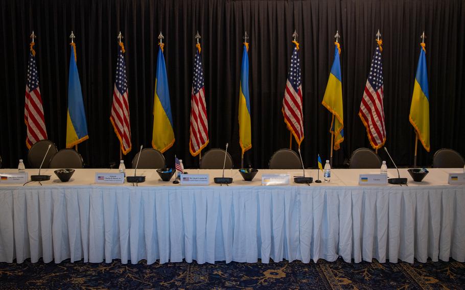 The flags of the United States and Russia stand behind a table.