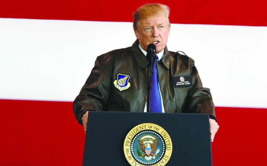 President Donald Trump stands in front of a microphone at a podium to speak at Yokota Air Base.