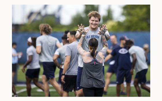 ODU offensive lineman Keanon McNally high-fives Britteney Powers at the conclusion of a joint workout with the Navy VFA 106 Demo Team at the L.R. Hill Sports Complex in Norfolk on Thursday, June 20, 2024. (Kendall Warner / The Virginian-Pilot)