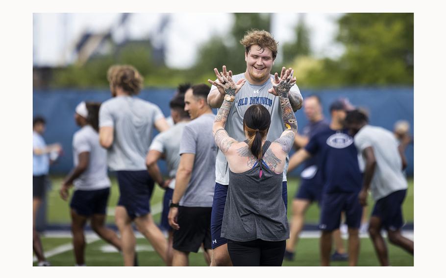 ODU offensive lineman Keanon McNally high-fives Britteney Powers at the conclusion of a joint workout with the Navy VFA 106 Demo Team at the L.R. Hill Sports Complex in Norfolk on Thursday, June 20, 2024. 