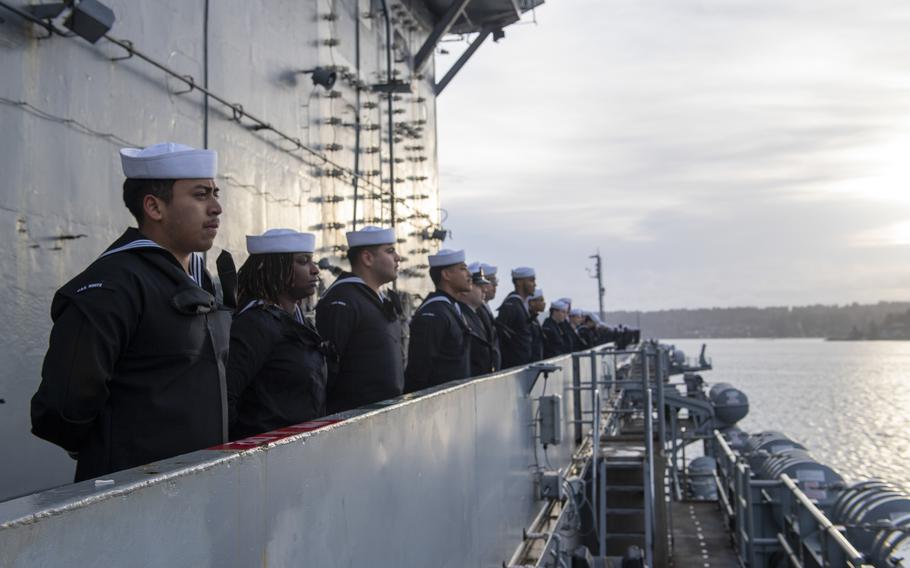 Sailors man the rails on the flight deck of an aircraft carrier