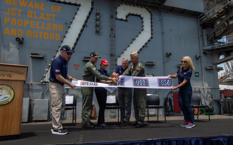 Vice Adm. Dan Cheever, commander, Naval Air Forces; Capt. Pete Riebe, commanding officer of Nimitz-Class aircraft carrier USS Abraham Lincoln; and USO representatives cut a ribbon during a ceremony to celebrate the opening of the USO center aboard Abraham Lincoln. Abraham Lincoln is currently moored at Naval Air Station North Island in San Diego. 