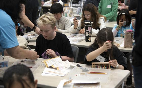 Defense Department elementary school students build sorobans during a workshop at the Tsukazan Community Center and Museum in Haebaru town, Okinawa, March 20, 2025.