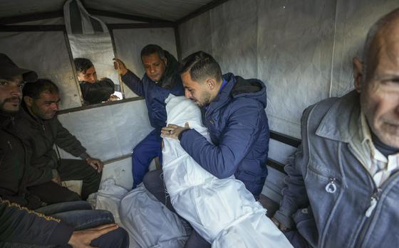 Mohammad Eid carries the body of one of his three relatives killed on Saturday in an Israeli airstrike, as they are prepared for the funeral in Deir al-Balah, central Gaza Strip, Sunday, Jan. 12, 2025. (AP Photo/Abdel Kareem Hana)