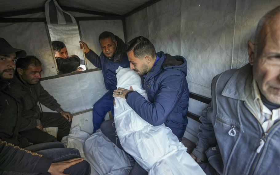 Mohammad Eid carries the body of one of his three relatives