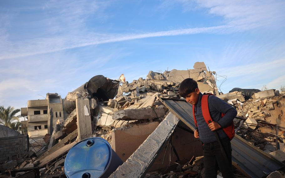 A boy walks past a destroyed building in the aftermath of an Israeli strike.