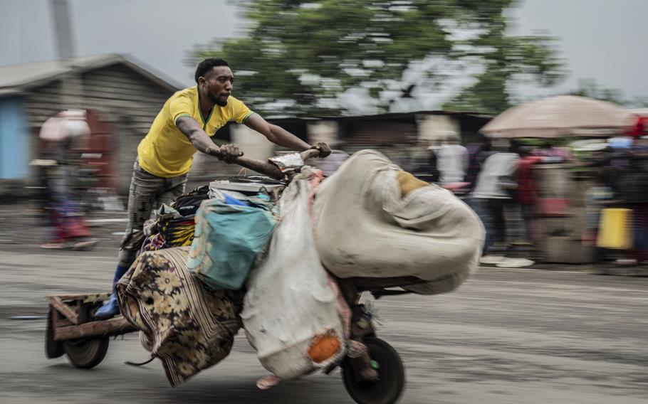 A man rides a motorcycle piled full with possessions.