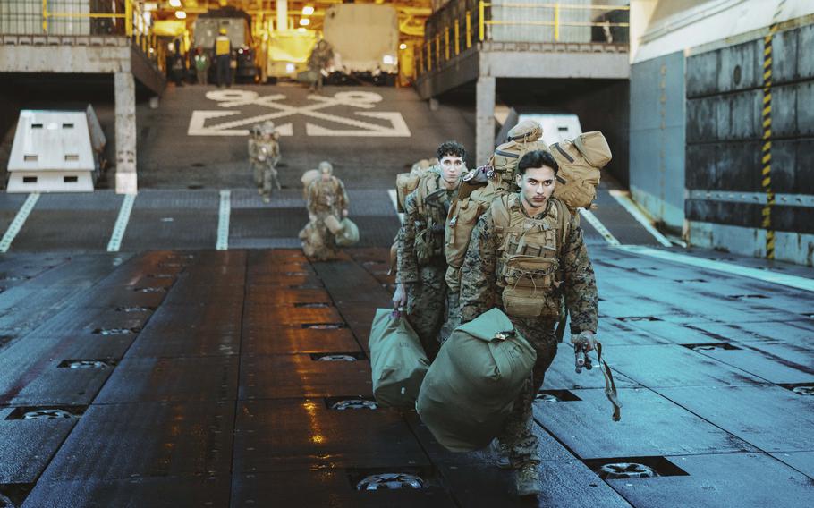 Marines carry their bags to a landing craft