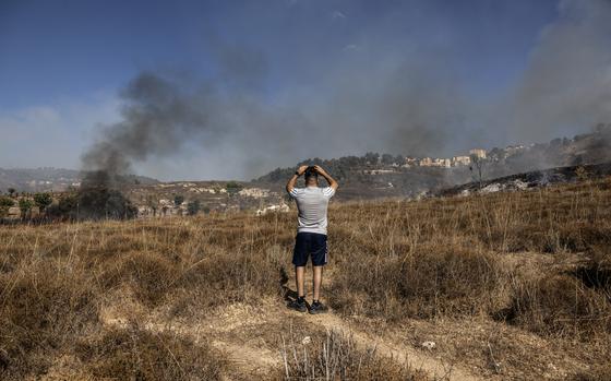 A man uses his phone to film the plumes of black smoke following a rocket attack fired from Lebanon along the Israeli border on Saturday.