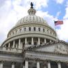 The dome of the U.S. Capitol building, seen from below, with a U.S. flag flying next to it.