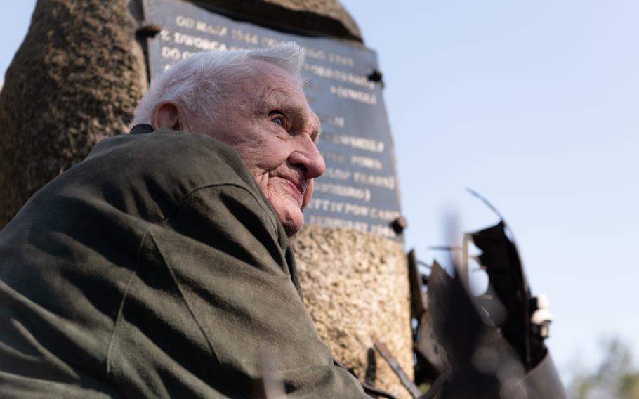 Lester Schrenk in front of a memorial plaque.