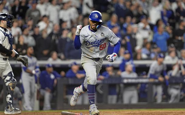 A baseball player raises a fist in celebration as he runs on the baseball diamond.