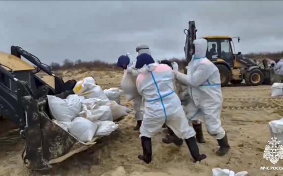 In this photo taken from video released by Russian Emergency Ministry Press Service on Saturday, Jan. 4, 2025, rescuers and volunteers work to clean up tons of fuel oil that spilled out of two storm-stricken tankers more than two weeks ago in the Kerch Strait, in Russia's southern Krasnodar region. (Russian Emergency Ministry Press Service via AP)