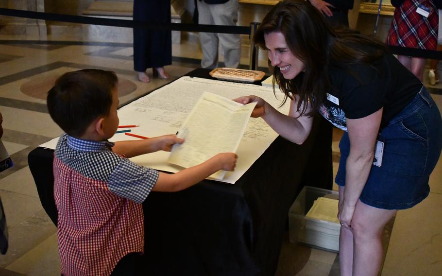 A young boy receives a replica of the Declaration of Independence after signing another replica inside the National Archives on July 4, 2024.