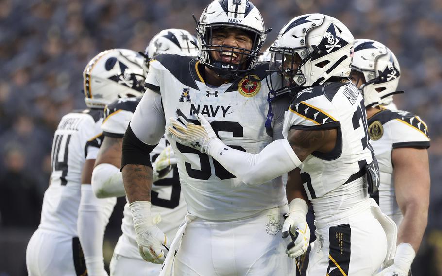 A Navy player smiles and is embraced by a teammate.