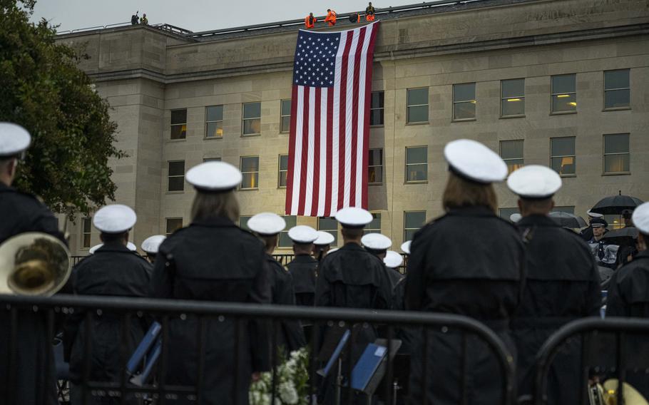 Pentagon officials unfurl an American flag over the side of the Pentagon at sunrise at an observance ceremony at the National 9/11 Pentagon Memorial to honor the 184 lives lost in the 2001 terrorist attack on the Pentagon, Washington, D.C., Sept. 11, 2023.