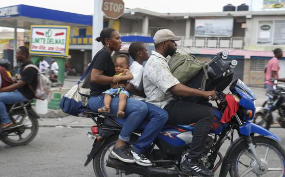 Two adults with two children ride on a motorcycle through a street in Port-au-Prince, Haiti, Nov. 14, 2024. 