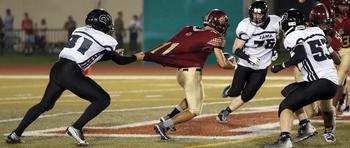 Matthew C. Perry's Kameron Ramos gets hemmed in by Zama defenders Caleb Schmiedel, Jefferey Woolard and during Friday's DODEA-Japan footballl game. The Trojans won 50-0.