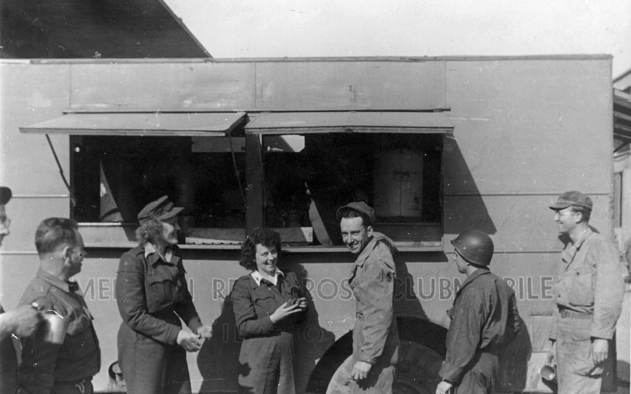 Elizabeth Richardson, left, with smiling troops in front of a clubmobile in Normandy, France. Richardson sent this photo to her parents on June 4, 1945, noting that the blur in her left hand is a donut.