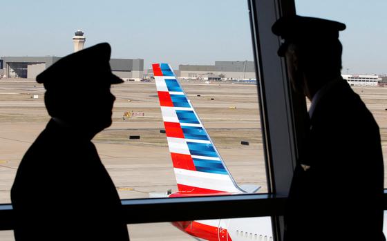 FILE PHOTO: Pilots talk as they look at the tail of an American Airlines aircraft at Dallas-Fort Worth International Airport February 14, 2013. REUTERS/Mike Stone/File Photo