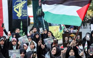 A woman waves a Palestinian flag while others hold posters showing a drawing of Yahya Sinwar, Palestinian Hamas' leader who was killed by Israel in southern Gaza on Oct. 16, during an anti-Israel rally in Tehran on Oct. 24, 2024. (-/AFP via Getty Images/TNS)