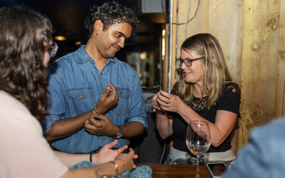 Jaibin Mathew, 23, gives Silly Bandz to April Thompson after his vibrant ’70s-themed Canva presentation on the bracelets.  “I think [the PowerPoints] are a really fun social lubricant because then they know something about you that they can ask you about,” Mathew said later in a phone interview. “And then it’s like a really great conversation starter.”