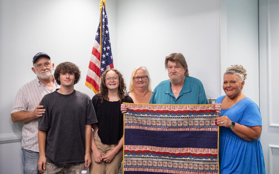 The family members of U.S. Army Pfc. Mose E. Vance pose with a homemade quilt gifted to them by a group of Gold Star Mothers at a private conference room at the Charlotte International Airport in Charlotte, N.C., July 31, 2024. 