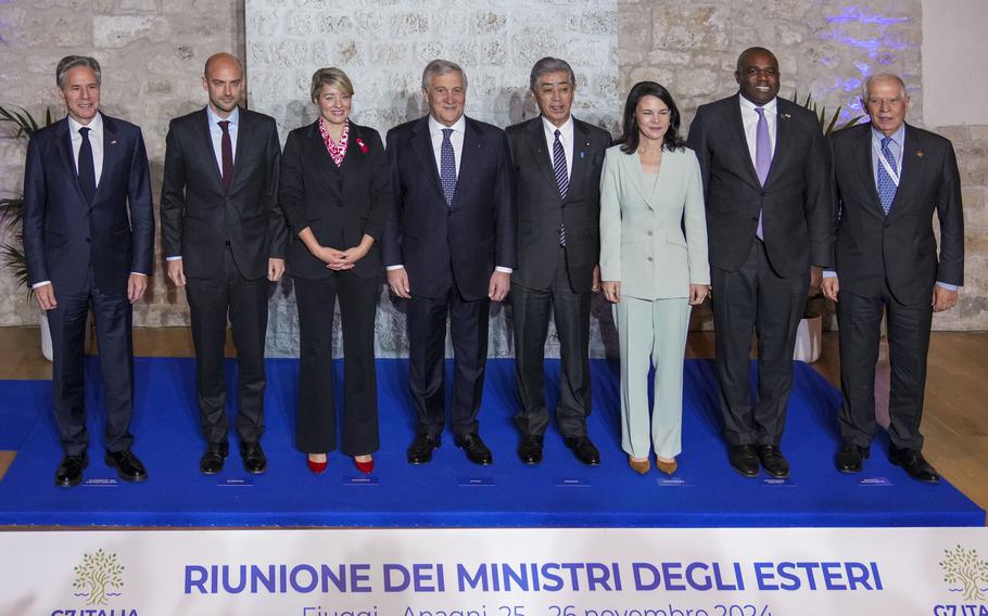 Eight foreign ministers representing the G7 and the E.U. pose for a photo on a slightly raised blue mat, Nov. 25, 2024.