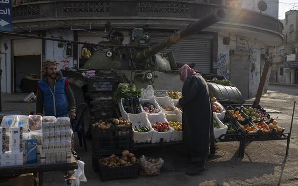 A person stands over racks of produce placed in front of a tank.