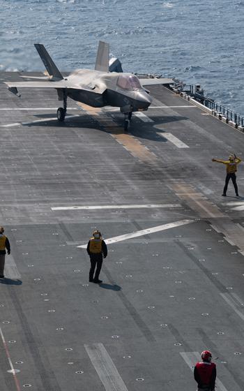 Sailors on deck as an F-35 taxis.