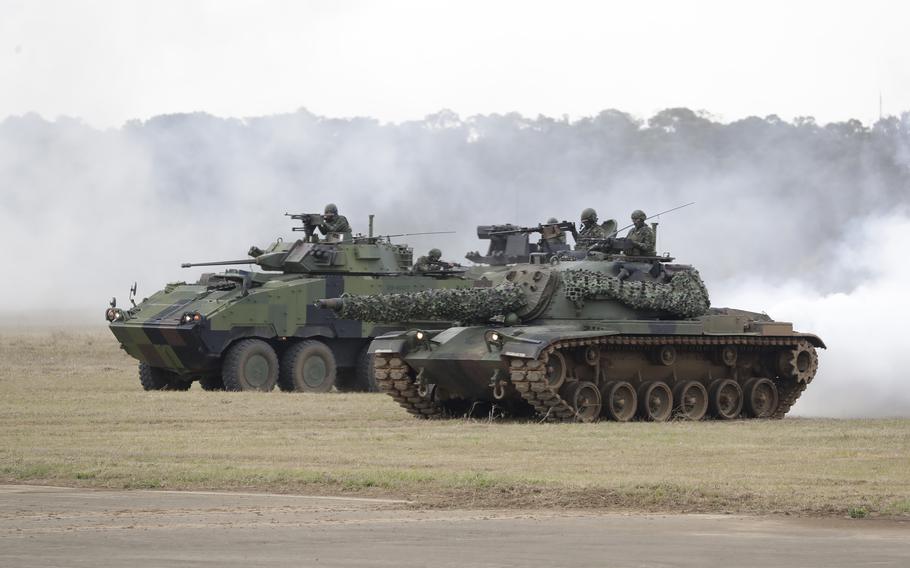 A tank and armored vehicle in a field.