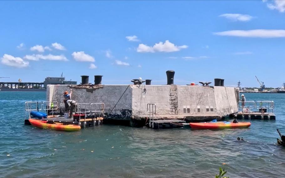 Workers with the National Park Service’s Historic Preservation Training Center stand on a floating dock beside a mooring quay in Pearl Harbor, Hawaii, in this screenshot of an NPS video taken in 2023.