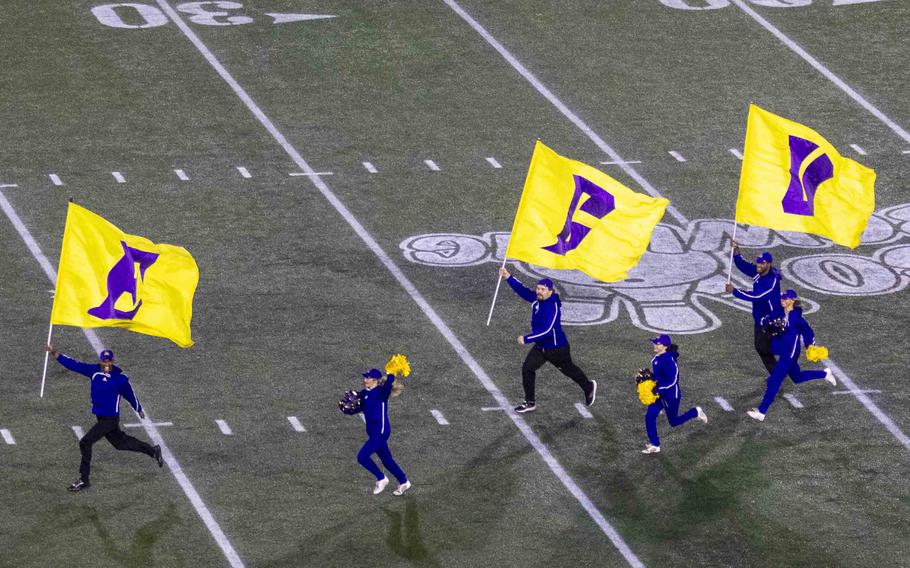 Spirit leaders run across the football field carrying flags.