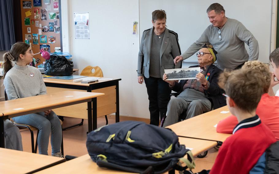 Ceo Bauer holds a photograph to schoolchildren in a classroom.