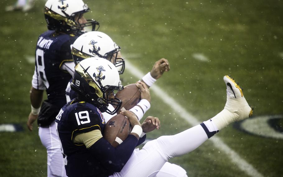 Navy players warm up before the game, wearing blue jerseys and white pants.