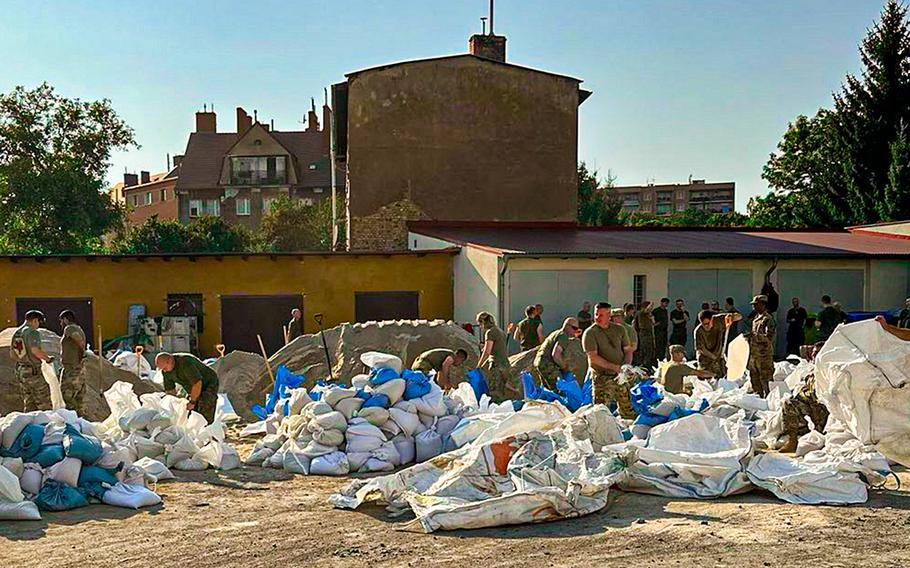 U.S. and Polish soldiers fill sandbags at Camp Karliki