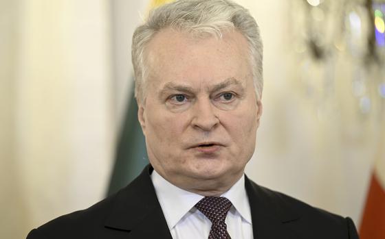 A portrait of a man in a suit and tie, with his lips parted slightly as he talks.