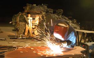 HED: Getting ready for Thunderdome, 2004

Camp Buehring, Kuwait, Aug. 17, 2004: Pfc. Mark Greene of the 699th Maintenance Company, 21, of North Carolina works on an armored door at the Camp Buehring "Mad Max" shop. The shop retro-fits soft-shelled vehicles of troops arriving from Germany, South Korea, Japan and elsewhere with armor, blast-proof windows and air conditioners so they stand a chance against jagged rocks, roadside bombs and the incessant Iraqi heat. 

During a tour of Camp Buehring just a few months later then Defense Secretary Donald Rumsfeld would field questions from Iraq-bound soldiers complaining about being sent into combat without armored vehicles, having to resort to "hillbilly armor," adding scavenged scrap metal and bullet proof glass on to their trucks for protection against roadside bombs in Iraq. 

Caught off guard by the critical questions, Rumsfeld uttered the now famous phrase "You go to war with the army you have, not the army you might want or wish to have at a later time."

Read about the inner workings of the "Mad Max" garage at Camp Buehring and see more photos here. 
https://www.stripes.com/migration/2nd-id-vehicles-are-upgraded-to-survive-rough-traveling-in-iraq-1.23450

META TAGS: Wars on Terror; armor shortage; U.S. Army; Operation Iraqi Freedom; logistics;
